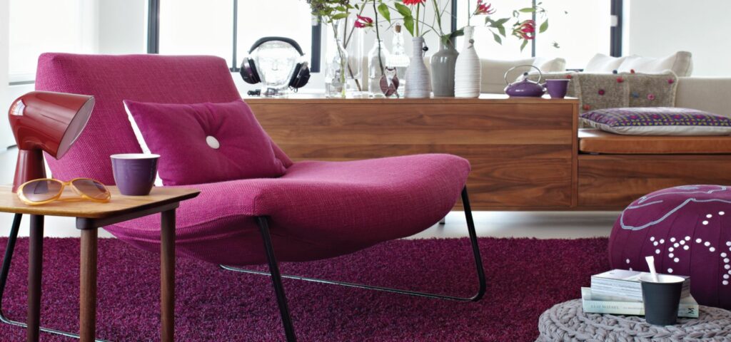 Ein Wohnzimmer mit einem lila Stuhl und einem Couchtisch. Firmenadresse