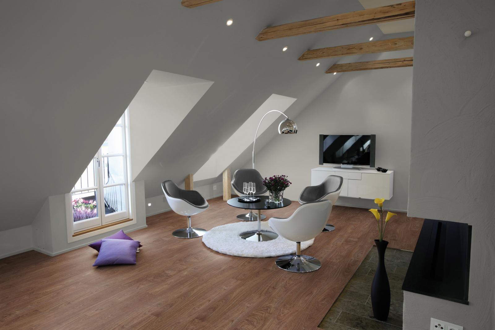Ein Wohnzimmer im Dachgeschoss mit Laminatboden. Firmenadresse