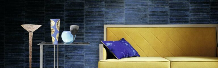 Ein gelb-blauer Stuhl vor einer blauen Wand. Firmenadresse
